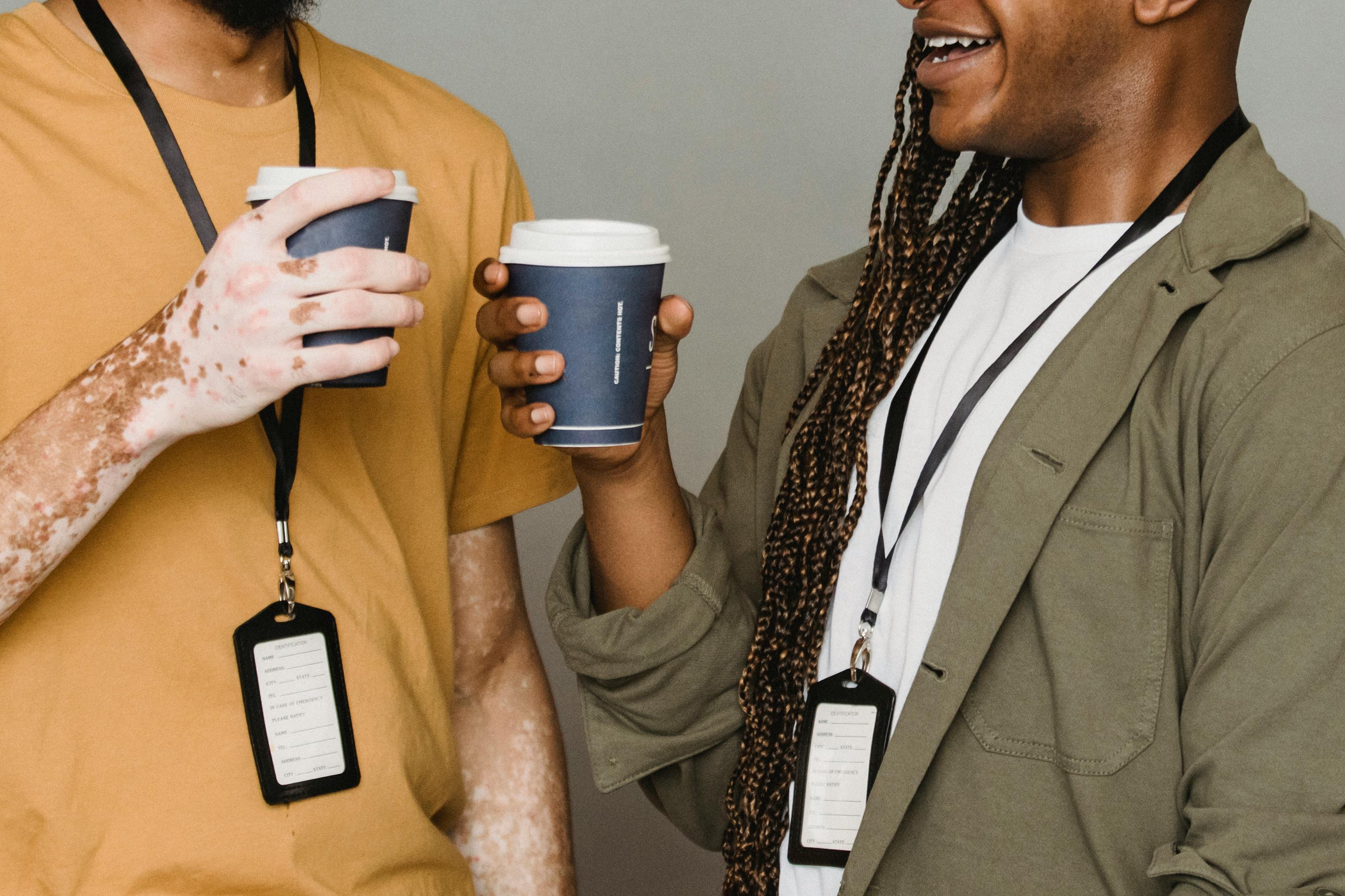 Two attendees laughing with lanyards and coffee